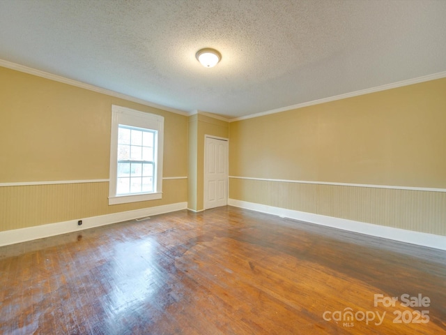 spare room featuring hardwood / wood-style floors, a textured ceiling, and ornamental molding