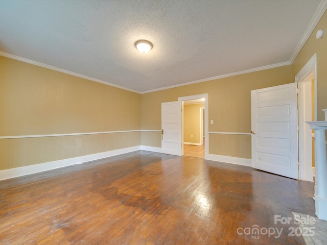 spare room featuring a textured ceiling, crown molding, and hardwood / wood-style flooring