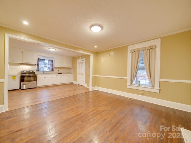 unfurnished living room with sink, hardwood / wood-style floors, a textured ceiling, and ornamental molding