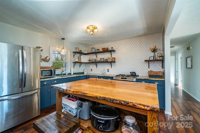 kitchen with pendant lighting, backsplash, stainless steel appliances, and blue cabinets