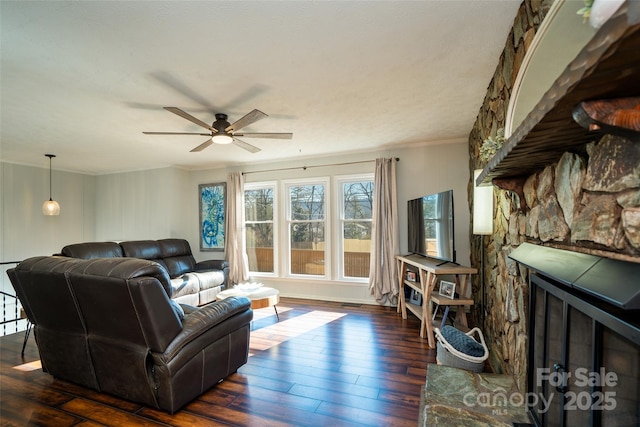 living room with a fireplace, dark hardwood / wood-style flooring, ceiling fan, and ornamental molding