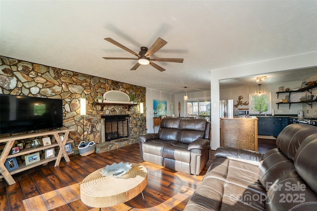 living room with a fireplace, ceiling fan, and dark wood-type flooring