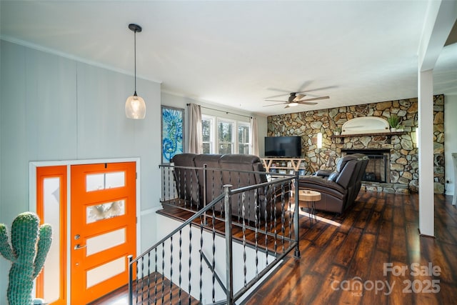 living room featuring ceiling fan, a fireplace, and dark wood-type flooring