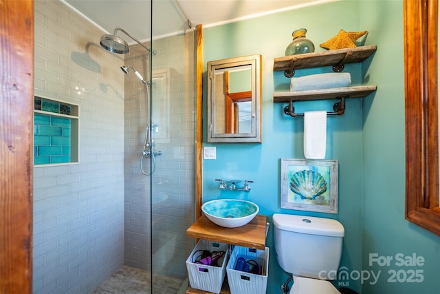 bathroom featuring toilet, sink, and tiled shower