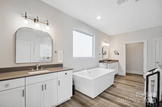 bathroom with hardwood / wood-style floors, vanity, and a tub to relax in