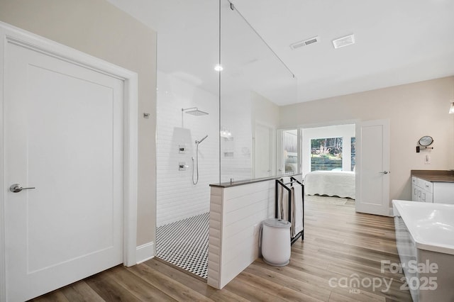 bathroom featuring a tile shower, vanity, and hardwood / wood-style floors