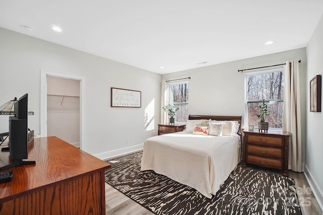 bedroom featuring light hardwood / wood-style flooring, a spacious closet, and a closet