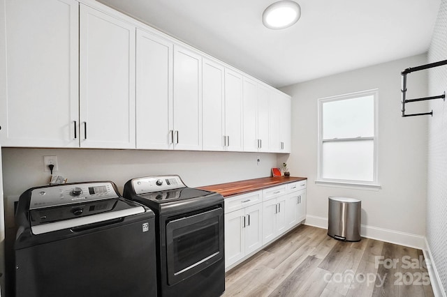 laundry room with light hardwood / wood-style floors, cabinets, and washing machine and dryer