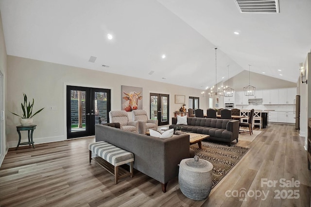 living room featuring french doors, hardwood / wood-style flooring, high vaulted ceiling, and a notable chandelier