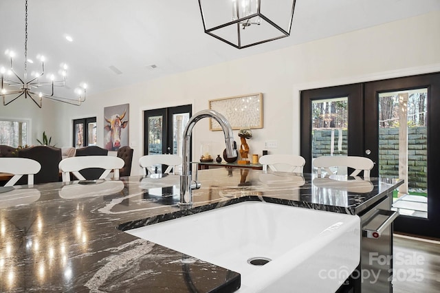 room details featuring french doors, decorative light fixtures, dark stone counters, and sink