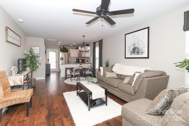 living room with ceiling fan with notable chandelier and dark wood-type flooring