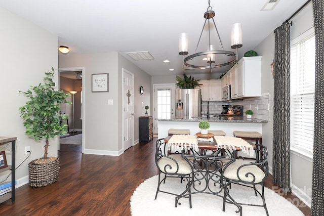 dining area with dark hardwood / wood-style floors, an inviting chandelier, and plenty of natural light