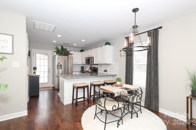 dining area with a chandelier, dark wood-type flooring, and sink