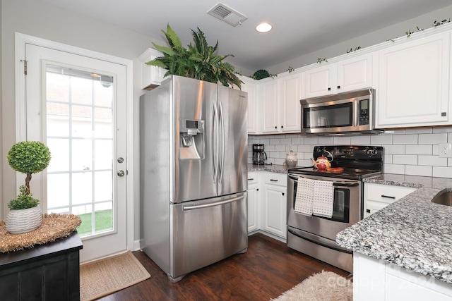 kitchen featuring backsplash, stone counters, dark wood-type flooring, white cabinets, and appliances with stainless steel finishes