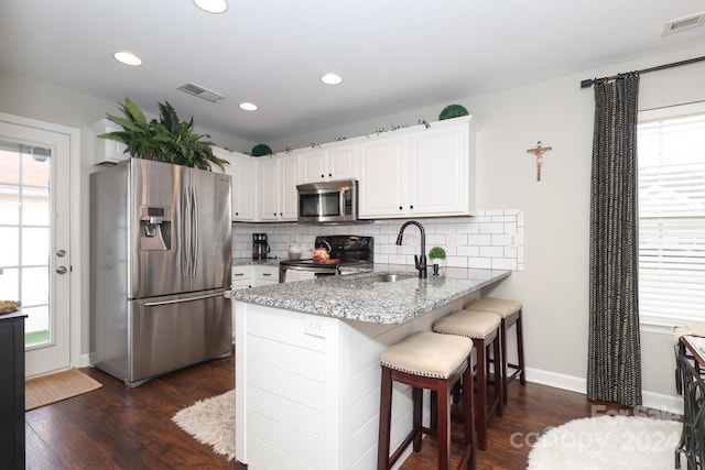 kitchen with a breakfast bar, white cabinets, sink, kitchen peninsula, and stainless steel appliances