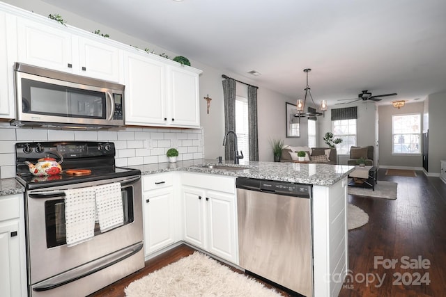 kitchen with kitchen peninsula, appliances with stainless steel finishes, white cabinets, and sink