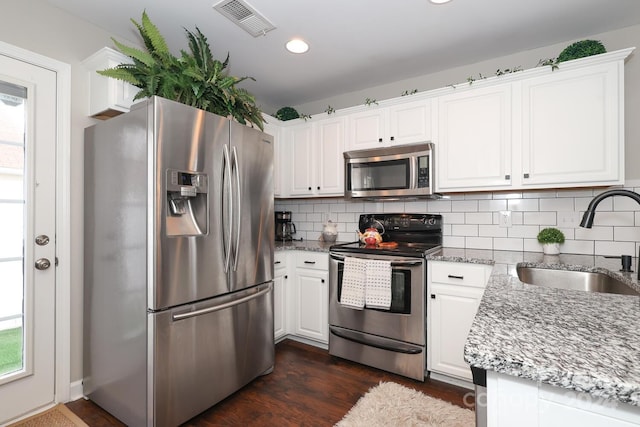 kitchen featuring white cabinets, sink, dark hardwood / wood-style flooring, light stone counters, and stainless steel appliances