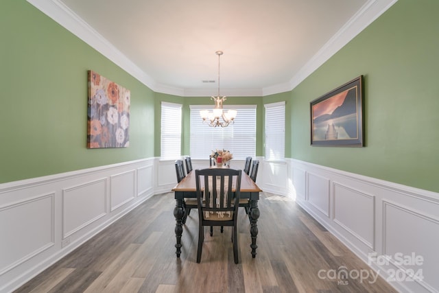 dining space featuring wood-type flooring, ornamental molding, and a chandelier