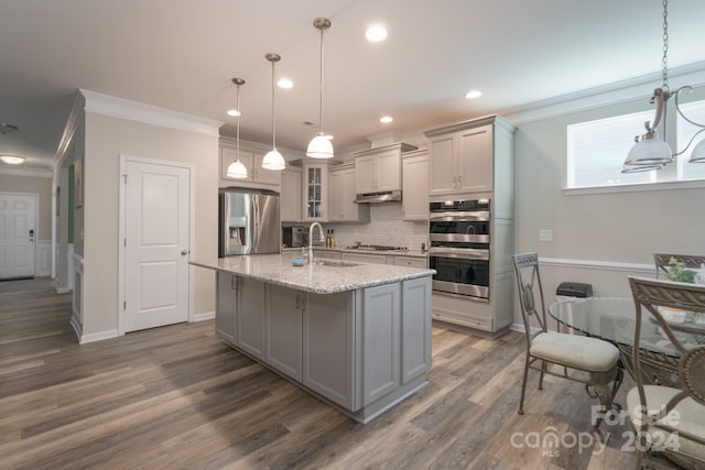 kitchen featuring appliances with stainless steel finishes, sink, a center island with sink, decorative light fixtures, and gray cabinets