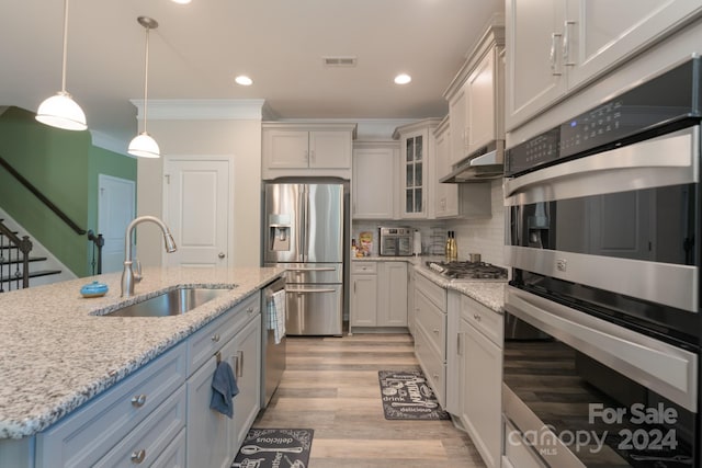 kitchen featuring light stone counters, stainless steel appliances, sink, decorative light fixtures, and white cabinets