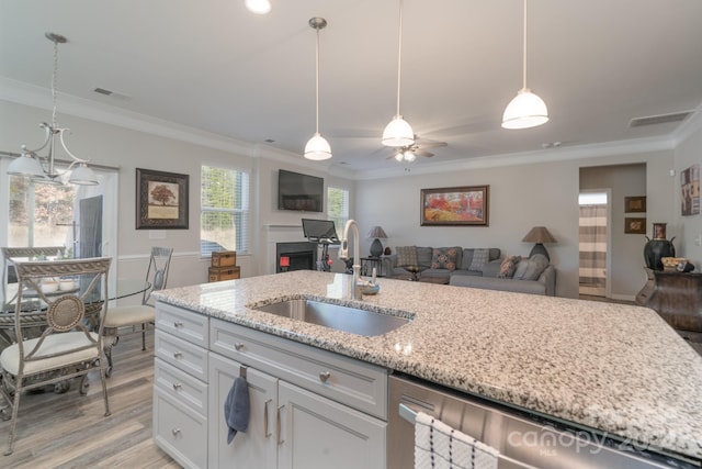 kitchen with light stone countertops, sink, decorative light fixtures, white cabinets, and ornamental molding