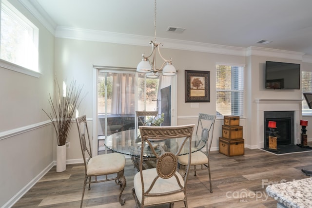 dining room featuring crown molding, wood-type flooring, and a notable chandelier