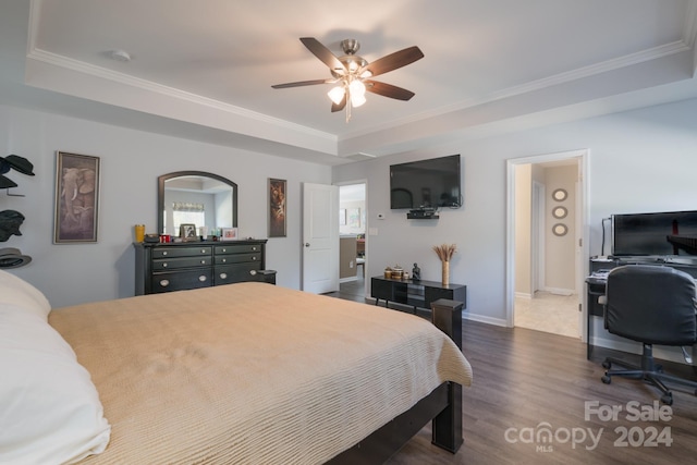 bedroom with hardwood / wood-style floors, ceiling fan, ornamental molding, and a tray ceiling