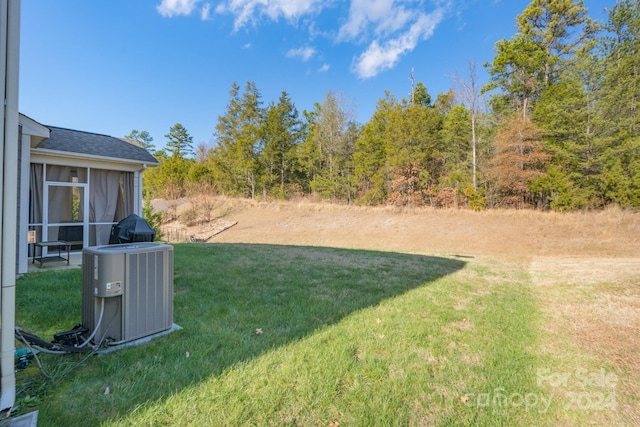 view of yard with central air condition unit and a sunroom