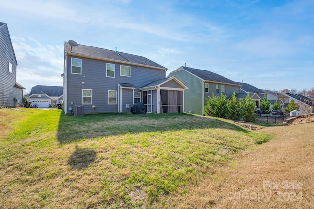 rear view of property with a sunroom, a yard, and central air condition unit