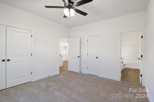 unfurnished bedroom with ceiling fan, light colored carpet, and ensuite bathroom