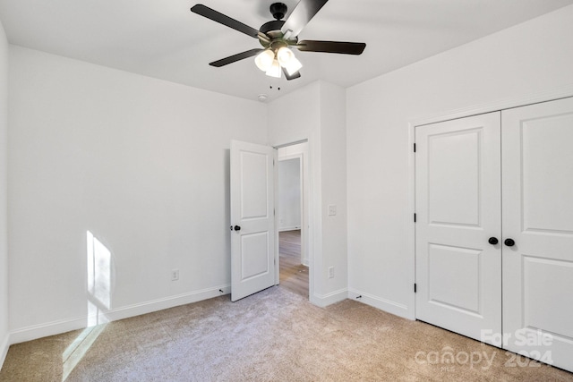 unfurnished bedroom with a closet, light colored carpet, and ceiling fan