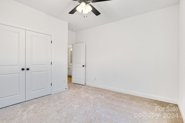 unfurnished bedroom with ceiling fan, a closet, and light carpet