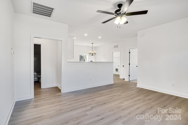 unfurnished living room with ceiling fan with notable chandelier and light hardwood / wood-style flooring