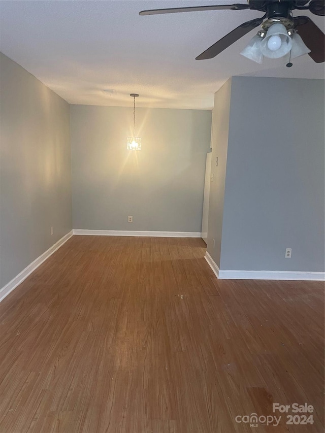 empty room with a notable chandelier and wood-type flooring