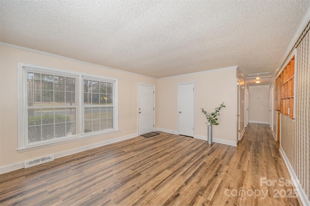 empty room featuring a textured ceiling, ornamental molding, and hardwood / wood-style floors