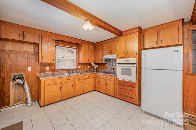 kitchen featuring sink, white appliances, beamed ceiling, and light tile patterned flooring