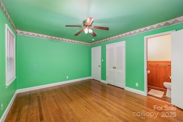 unfurnished bedroom with ceiling fan, wood-type flooring, and connected bathroom