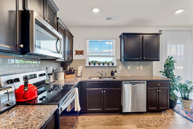 kitchen with stainless steel appliances, light stone counters, and sink