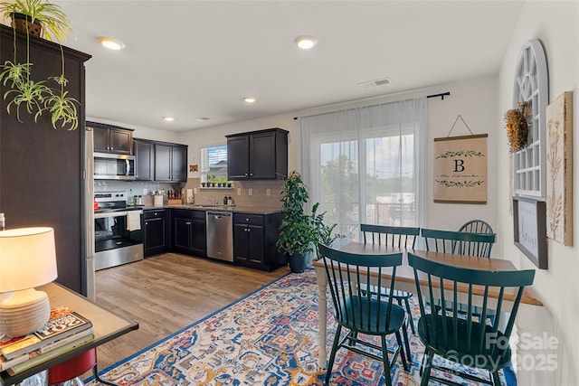 kitchen with stainless steel appliances, light hardwood / wood-style flooring, tasteful backsplash, and sink