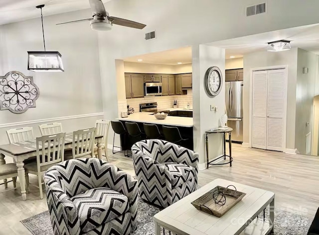 living room with light wood-type flooring, high vaulted ceiling, and ceiling fan