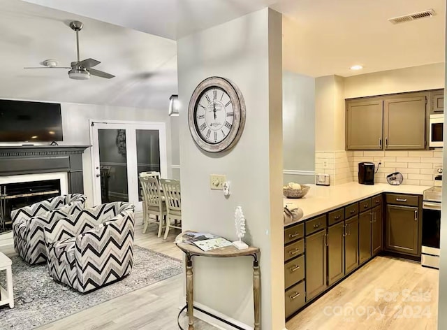 kitchen featuring dark brown cabinetry, ceiling fan, stainless steel range, backsplash, and light hardwood / wood-style floors