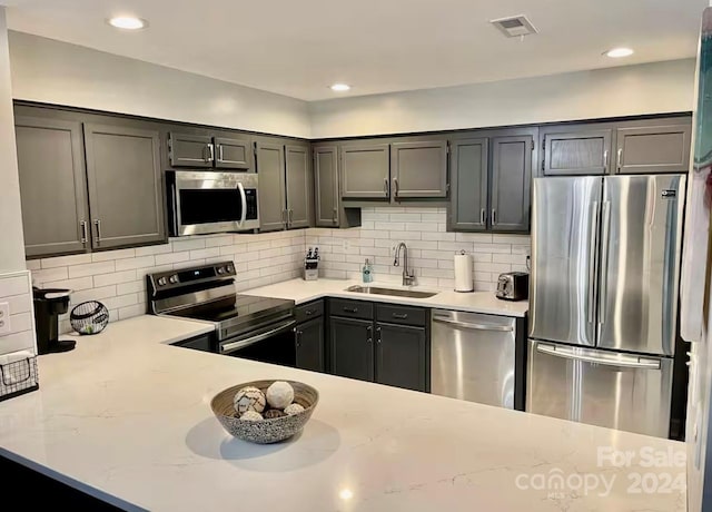 kitchen with decorative backsplash, sink, light stone counters, and stainless steel appliances