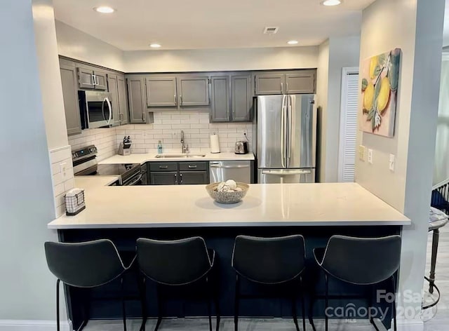 kitchen featuring a breakfast bar, sink, kitchen peninsula, and stainless steel appliances