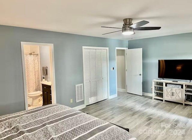 bedroom with ceiling fan, ensuite bath, light hardwood / wood-style flooring, and a closet