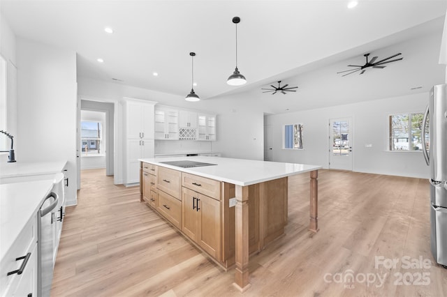 kitchen featuring a large island, pendant lighting, white cabinetry, stainless steel appliances, and light hardwood / wood-style floors