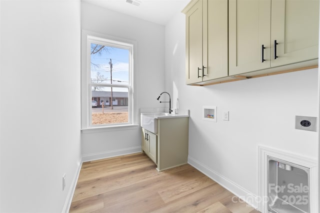 laundry area featuring sink, cabinets, washer hookup, hookup for an electric dryer, and light hardwood / wood-style flooring