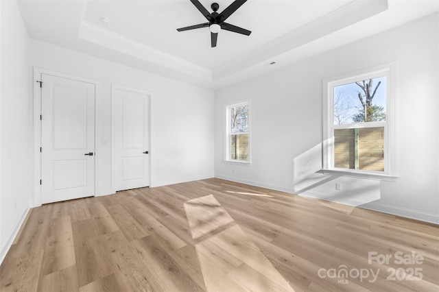 unfurnished bedroom featuring ornamental molding, a raised ceiling, ceiling fan, and light wood-type flooring