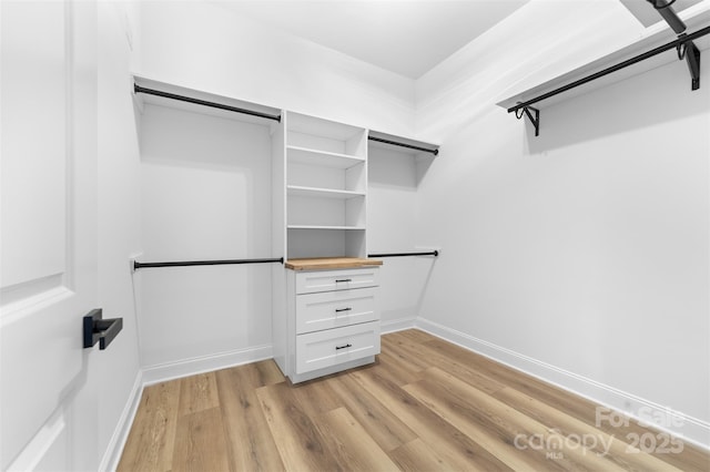 walk in closet with light hardwood / wood-style flooring