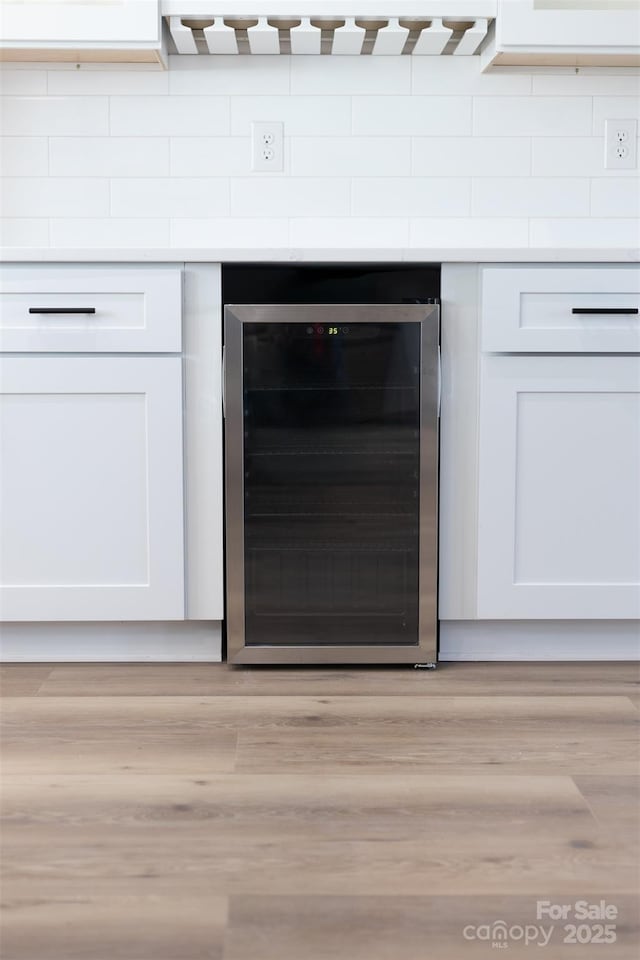 interior details with white cabinets, beverage cooler, and light hardwood / wood-style flooring