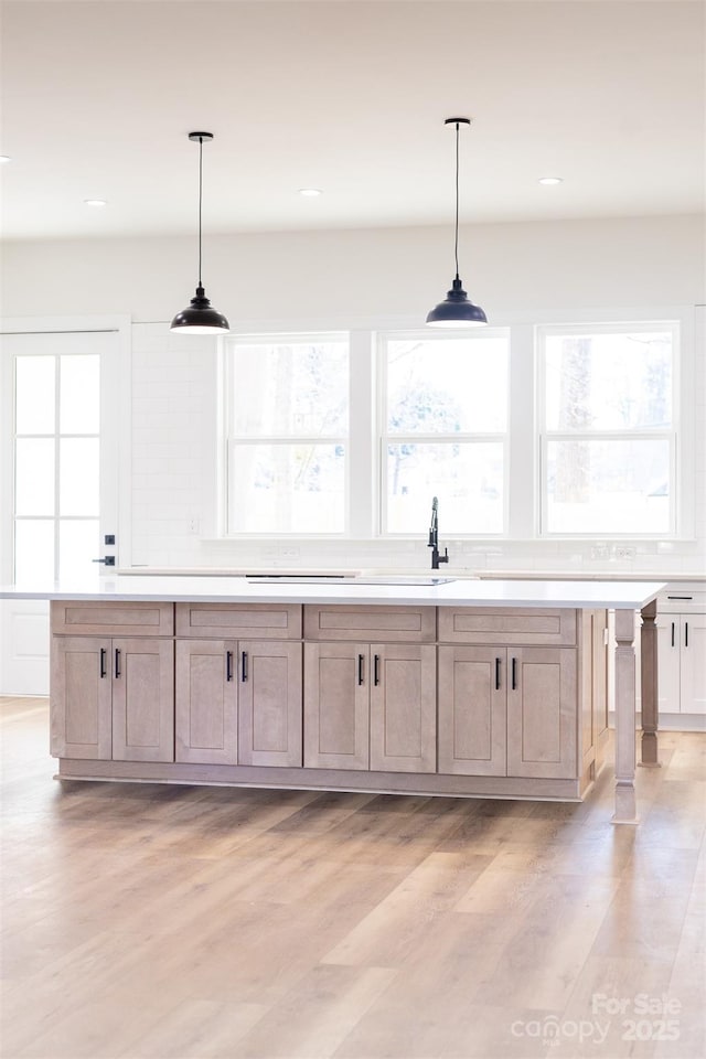 bar with pendant lighting, light brown cabinets, and light hardwood / wood-style floors